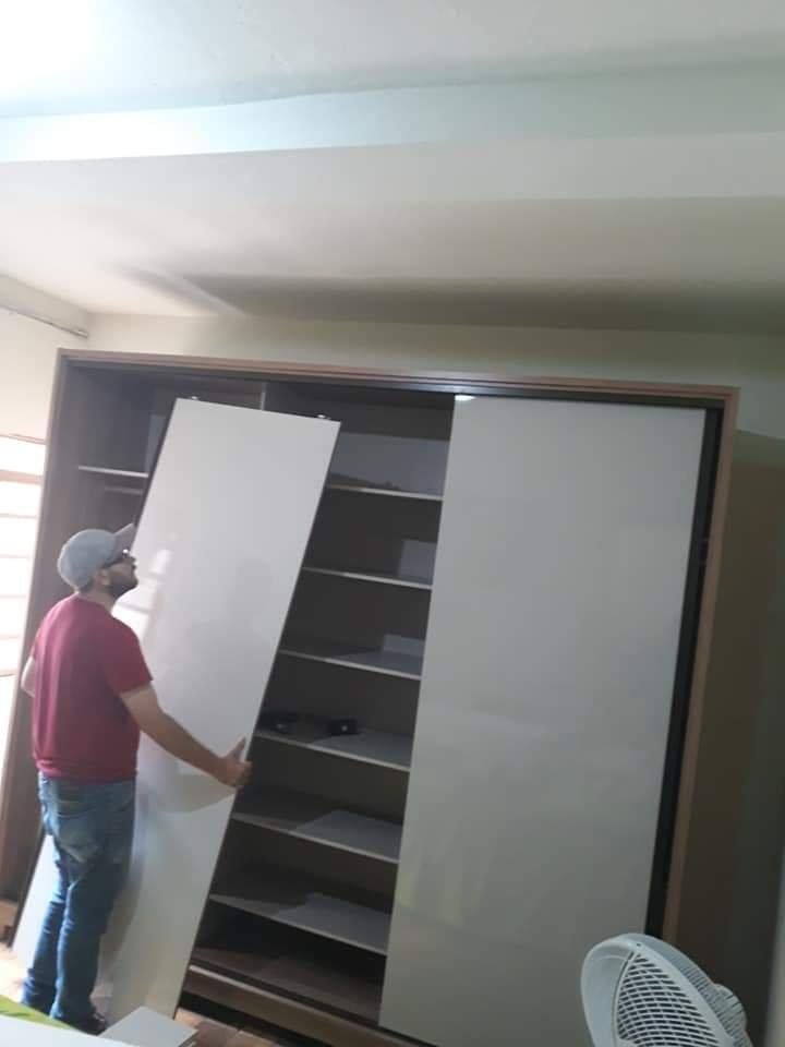 Montador de Moveis fazendo a desmontagem de 1 guarda roupa com portas de correr marrom e branco