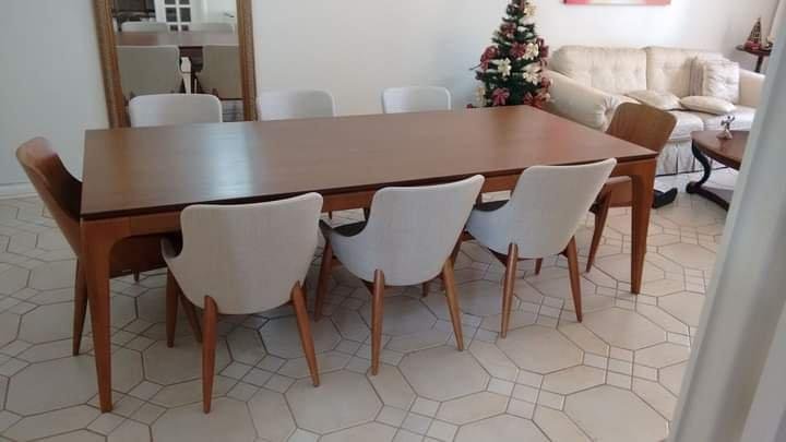 Mesa de Jantar 8 cadeiras Sala de jantar com mesa retangular de madeira e oito cadeiras estofadas em tecido claro, combinando com o piso cerâmico e a decoração moderna do ambiente. Ideal para espaços amplos e reuniões familiares